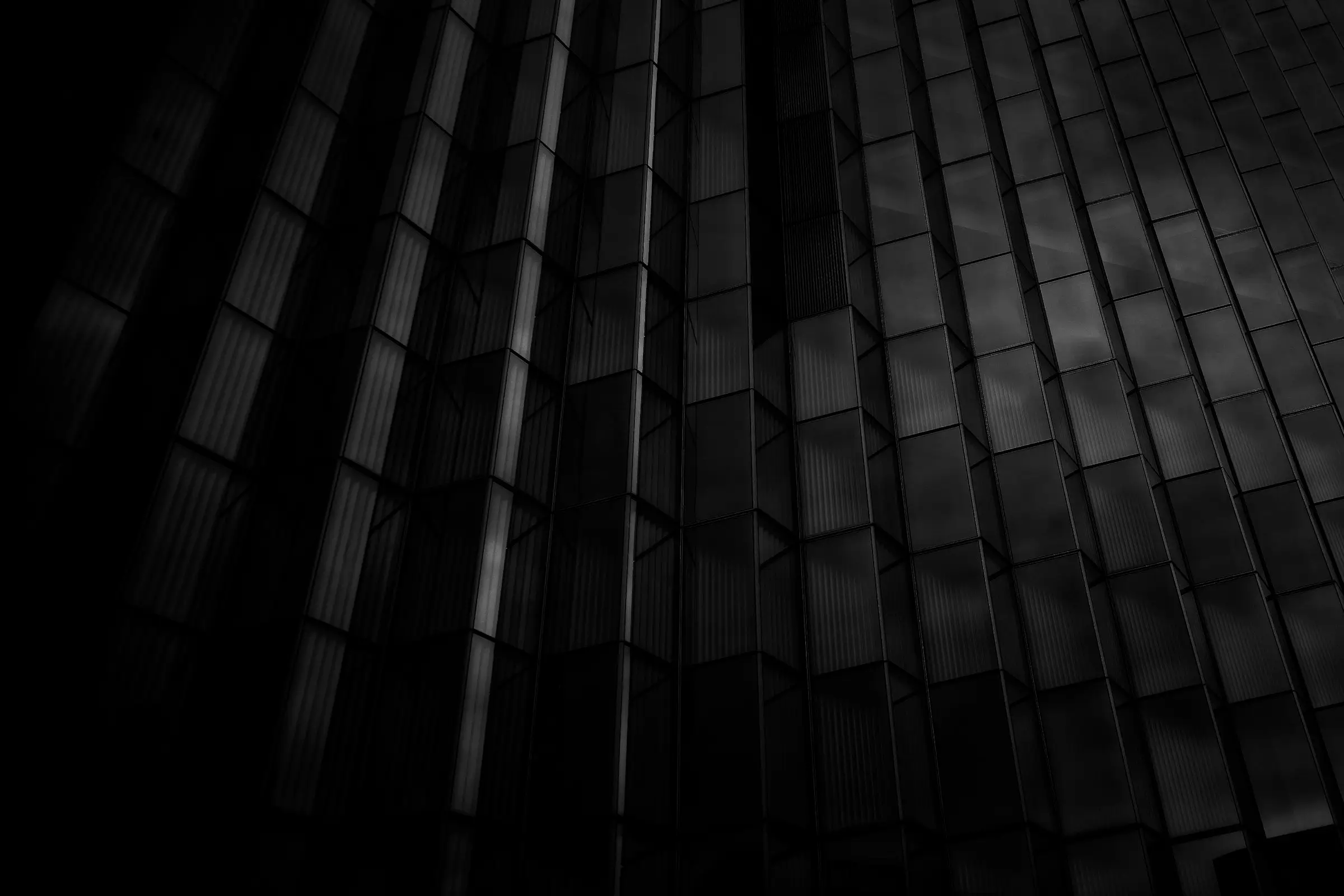 Dunkle geometrische Glasfassade als Sinnbild für digitale Struktur